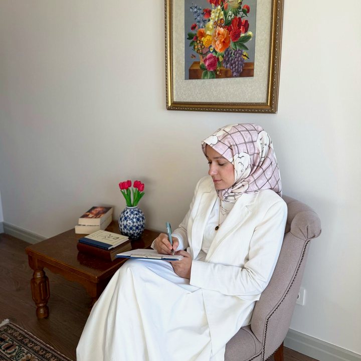 Huriye Çevik, görüşme odasında koltukta oturmuş not alıyor